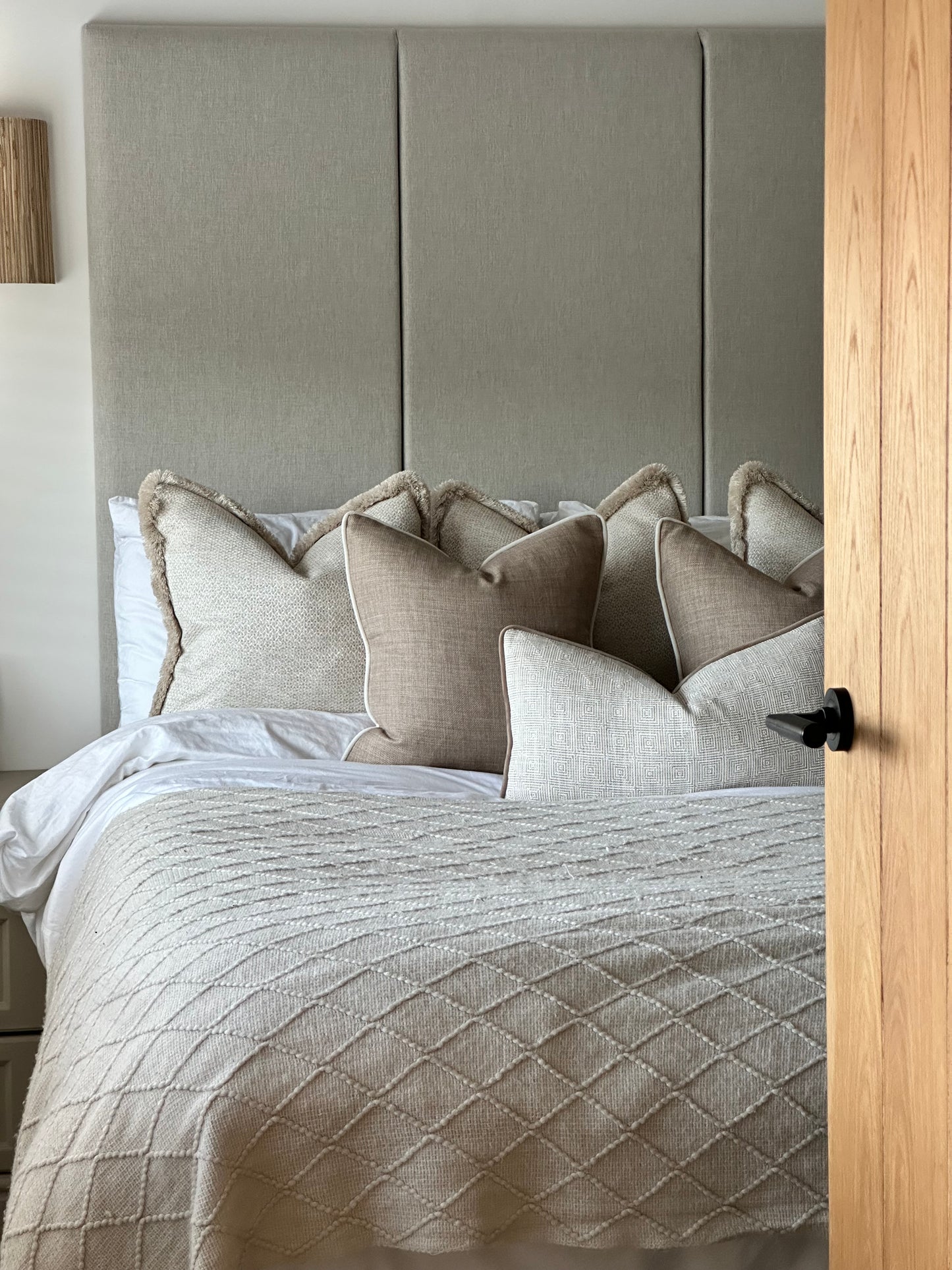 Neutral cushion set styled on a bed with fringed, piped, and lumbar cushions in beige and ivory tones.