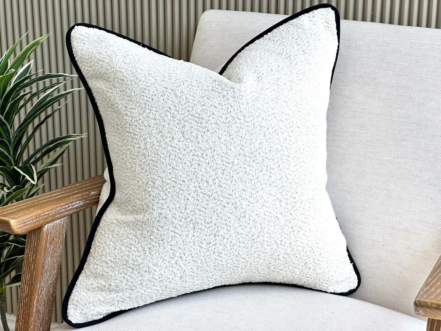 Ivory boucle cushion with a soft texture and black piping trim. Perfect for modern home decor.