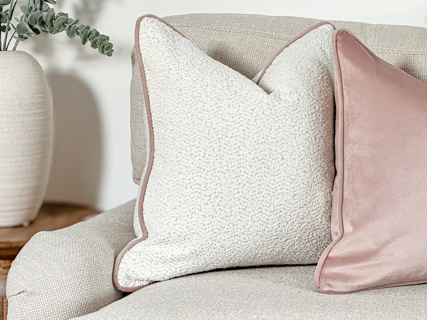 Ivory white boucle cushion cover with a blush pink piping next to a pink velvet cushion. Perfect for a baby girls nursery or girls bedroom decor.