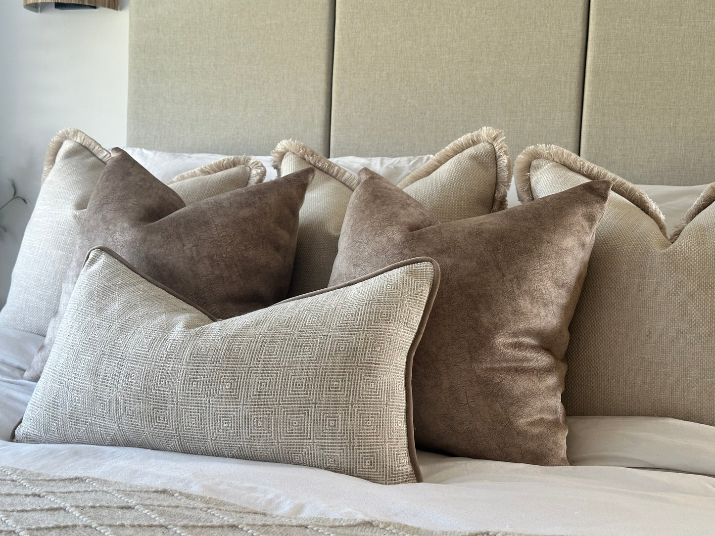 Beautiful cream and beige cushion combo and a bed that has a luxury headboard. Textured cushions and patterns add a layered look.