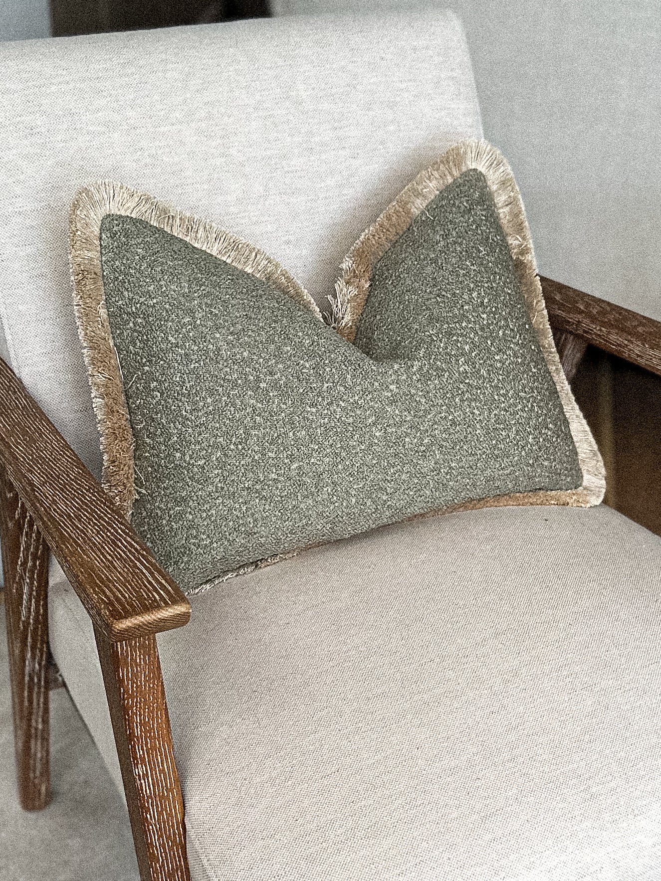 Muted earthy green boucle cushion cover with fringing.