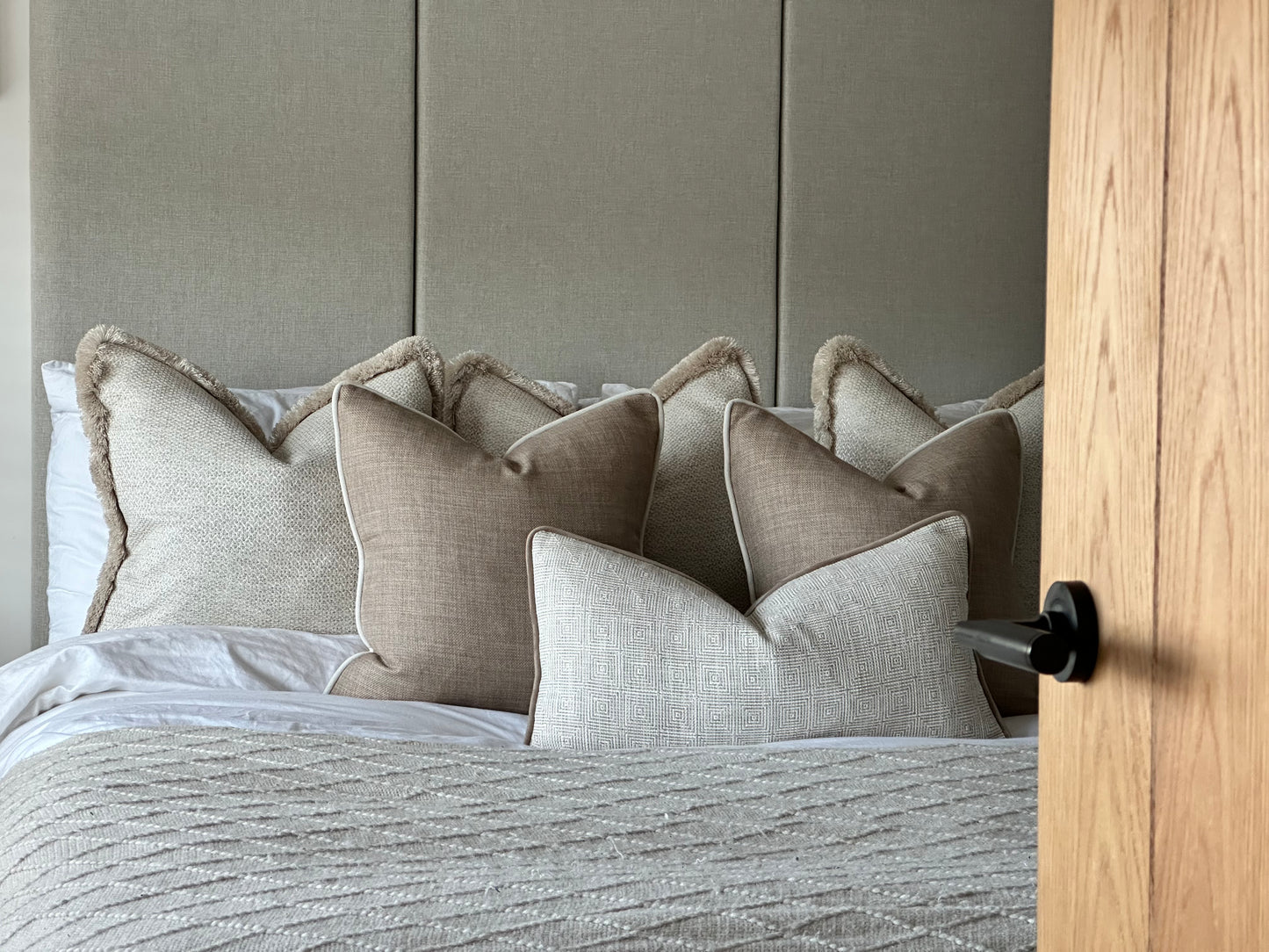 Six-piece cushion arrangement featuring Hallie, Alba Beige, and New England Natural cushions in a calm, neutral bedroom setting.