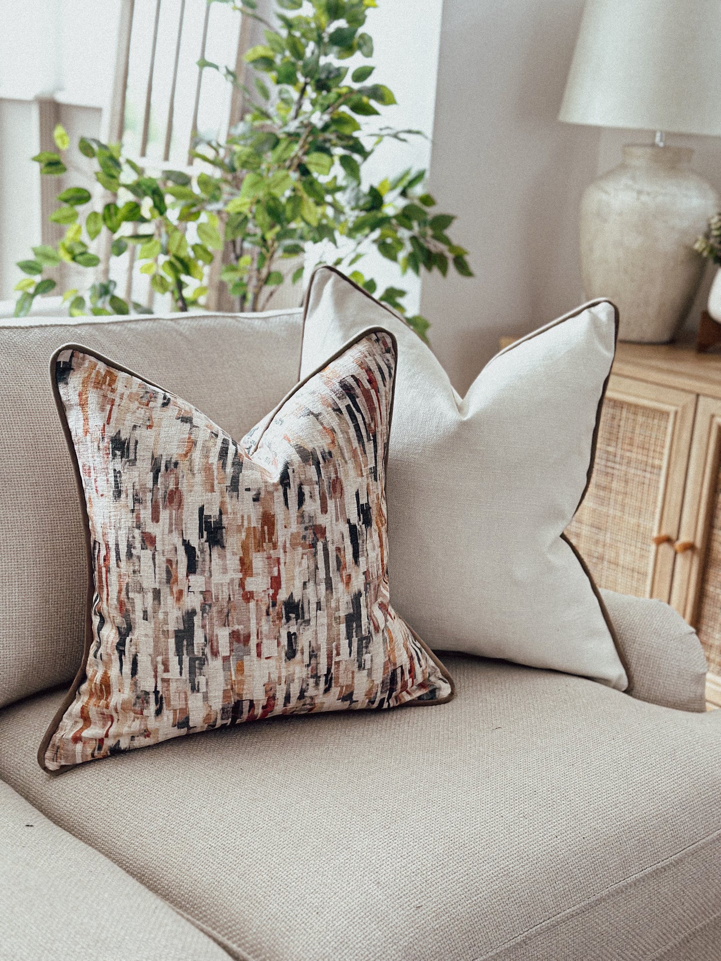 Terracotta and neutral scatter cushion with a painterly print — perfect for modern rustic living spaces.