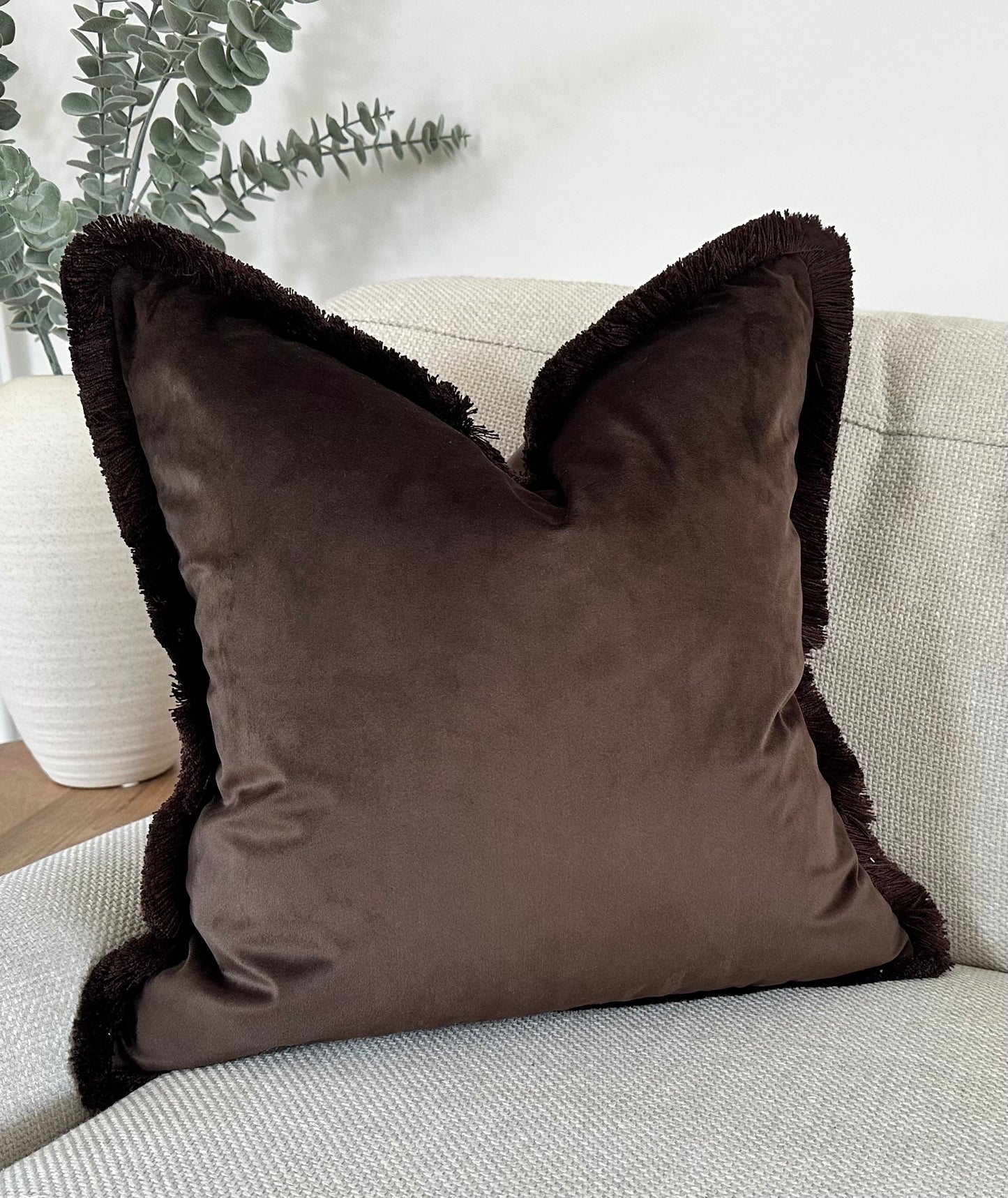 Dark brown velvet cushion cover with fringe.