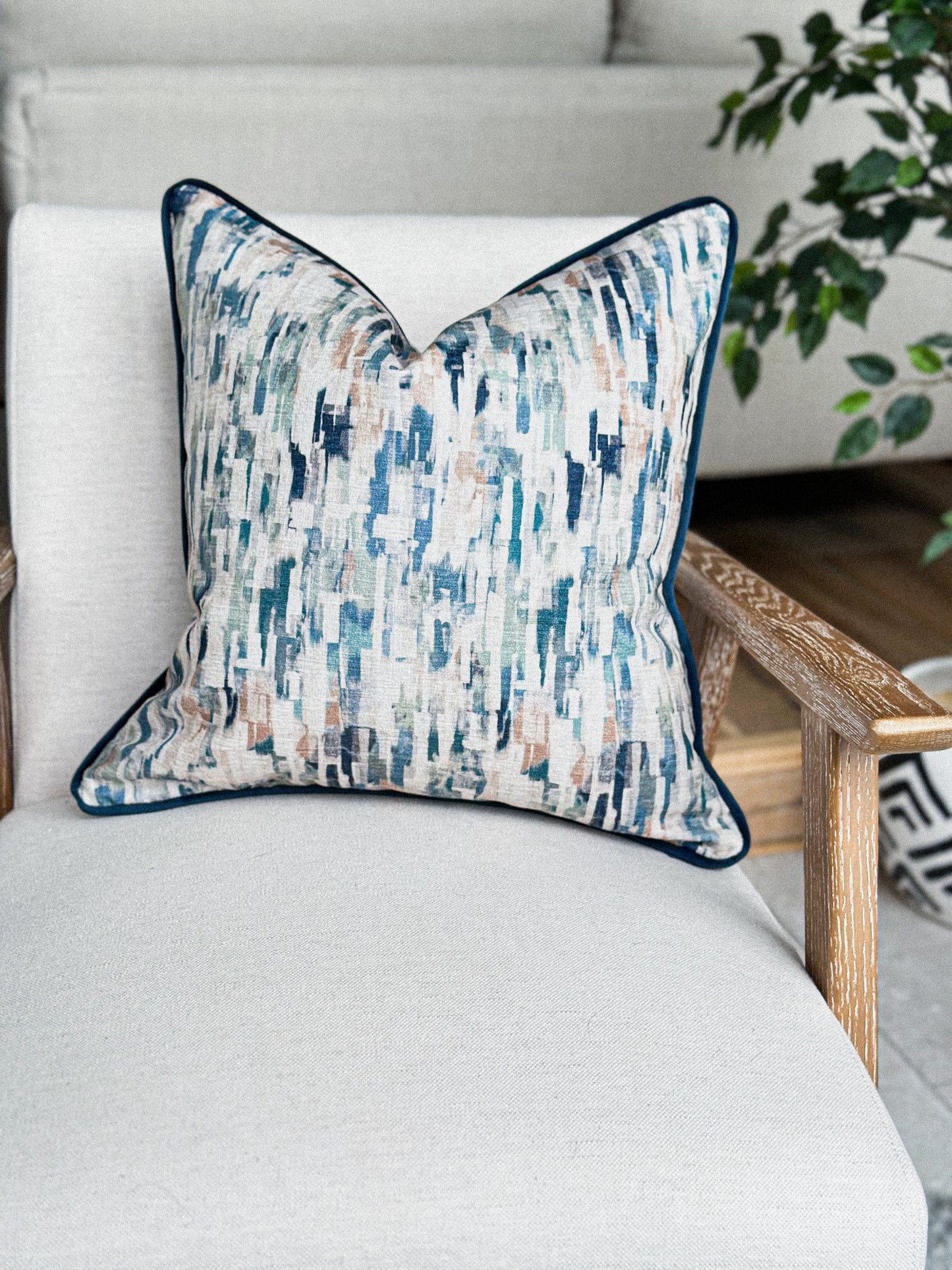 Scatter cushion in soft blue, green, and sand hues with a navy piped trim.