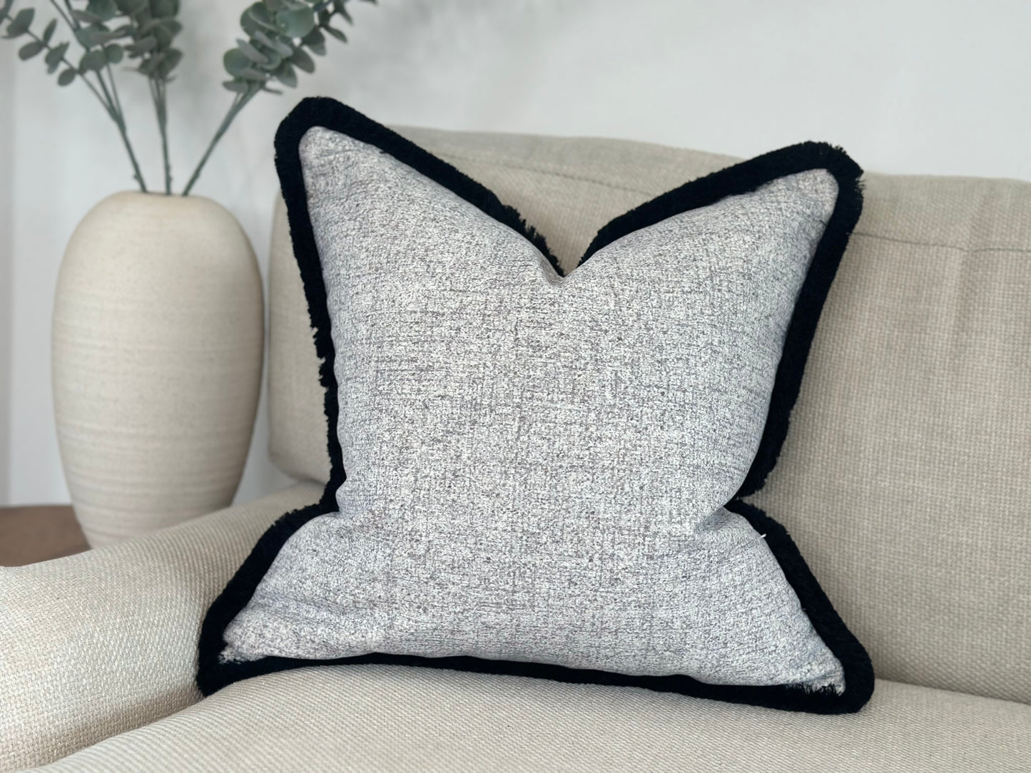 A stylish grey and white pillow with a contrast black trim, adding a modern accent to the decor.