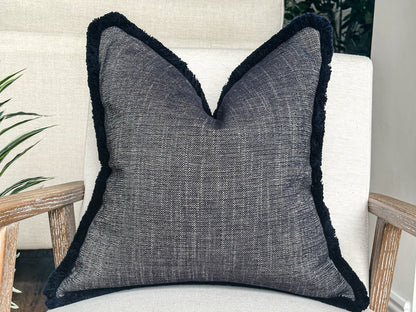 Blue textured pillow with fringe trim.