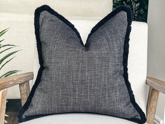 Blue textured pillow with fringe trim.