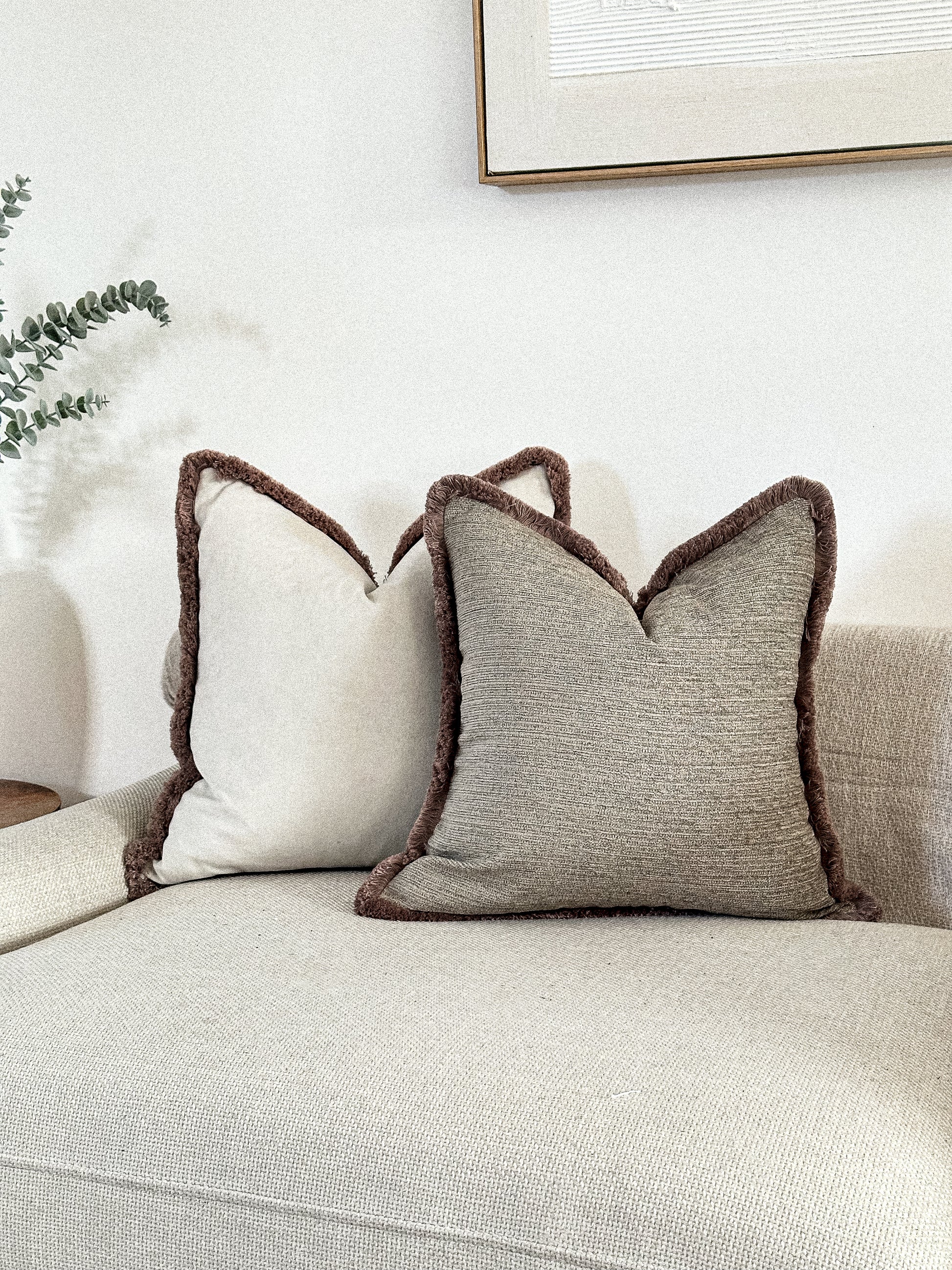 Textured beige throw pillow cover with fringing.