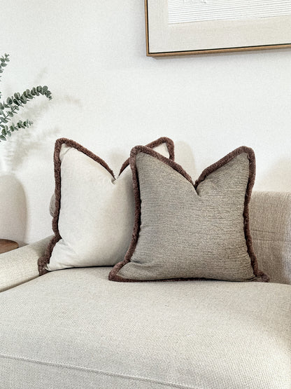 Textured beige throw pillow cover with fringing.