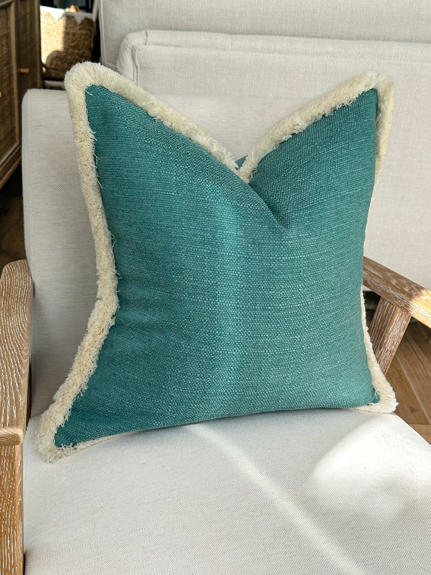 Turquoise scattered cushion with cream fringing.