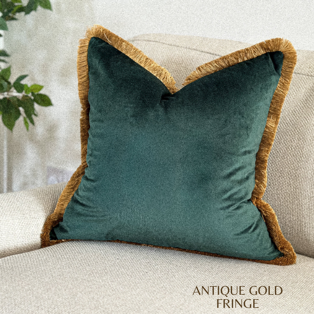 Dark green velvet throw pillow with fringed edge.
