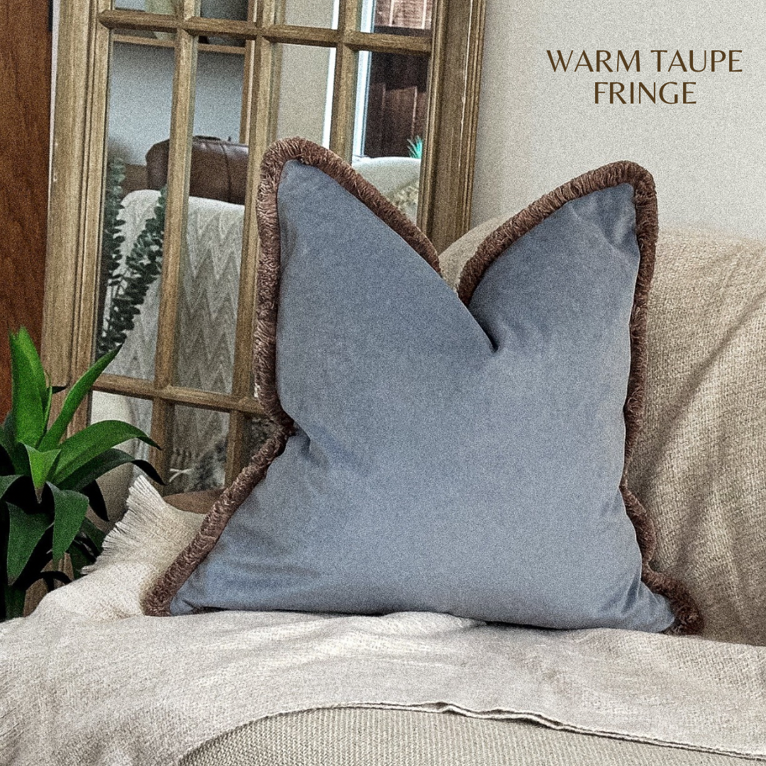 Muted blue velvet throw pillow cover with beige fringe trim.