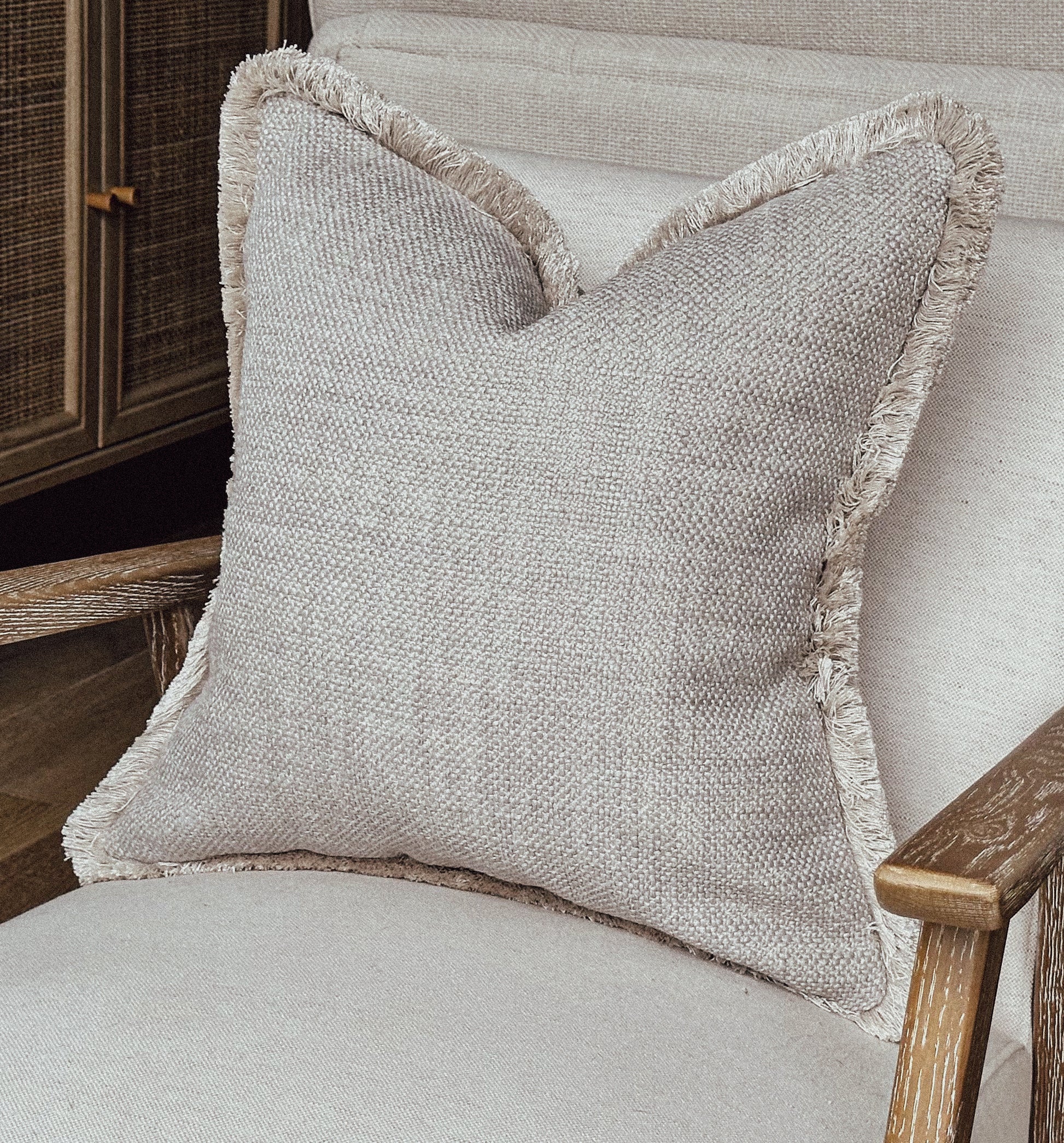 Greige textured cushion with fringe trim.