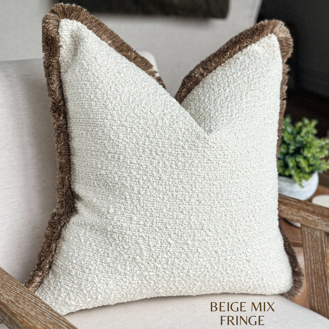 Cream boucle pillow with beige fringing.