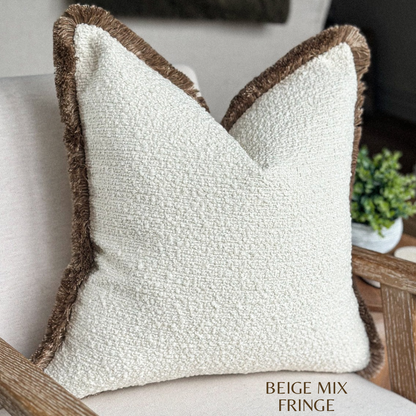 Cream boucle pillow with beige fringing.