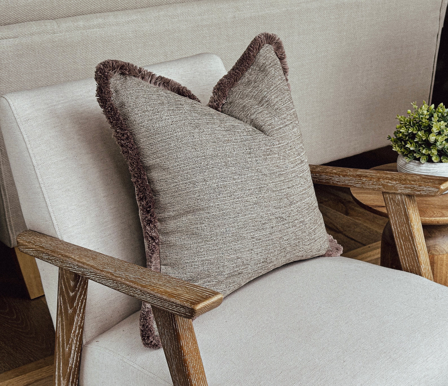 Beige textured fringed cushion.