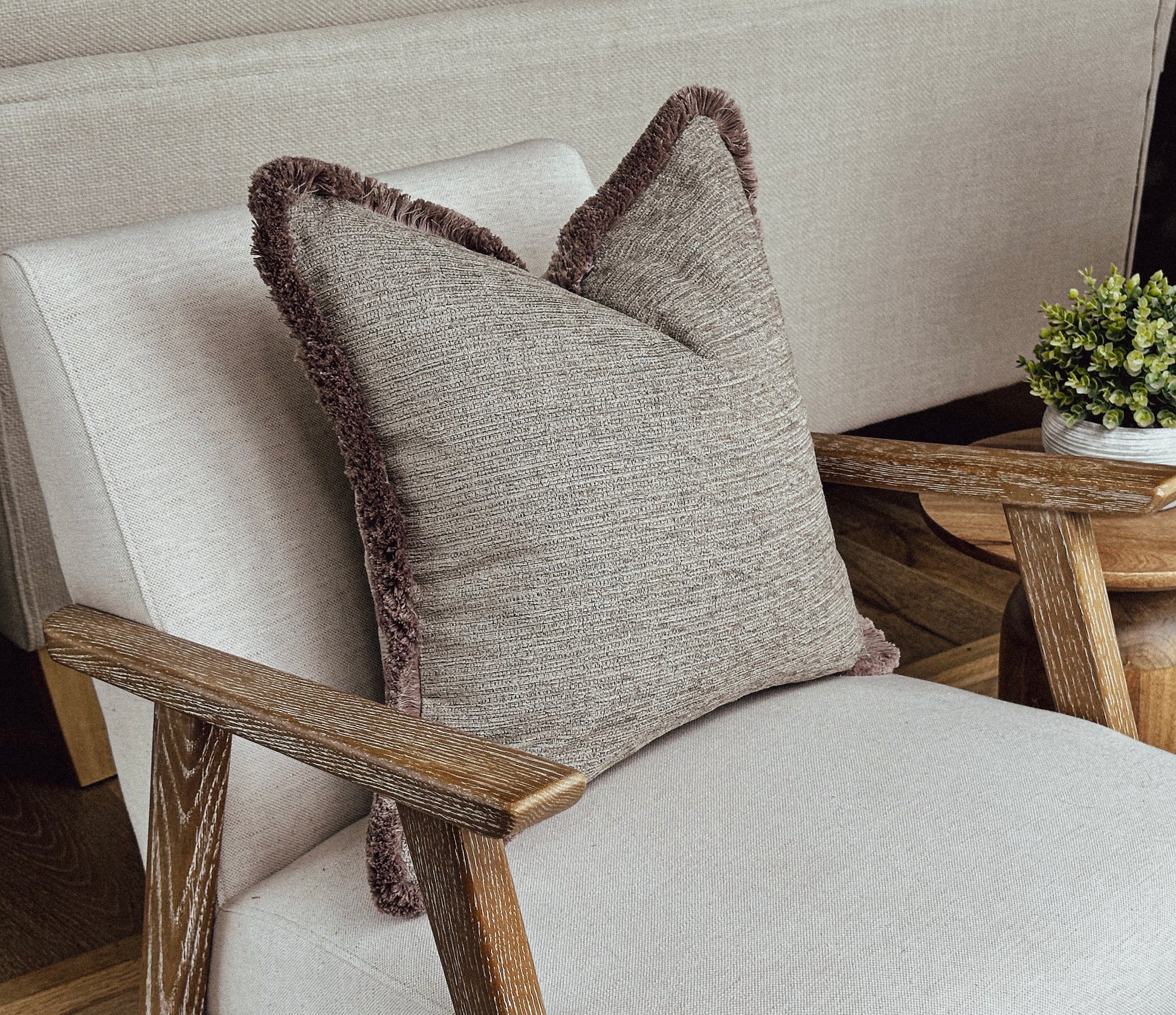 Beige textured fringed cushion.