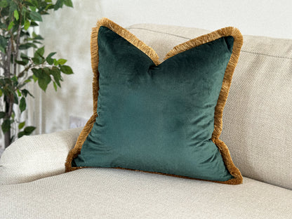 Dark green velvet throw pillow with fringed edge.