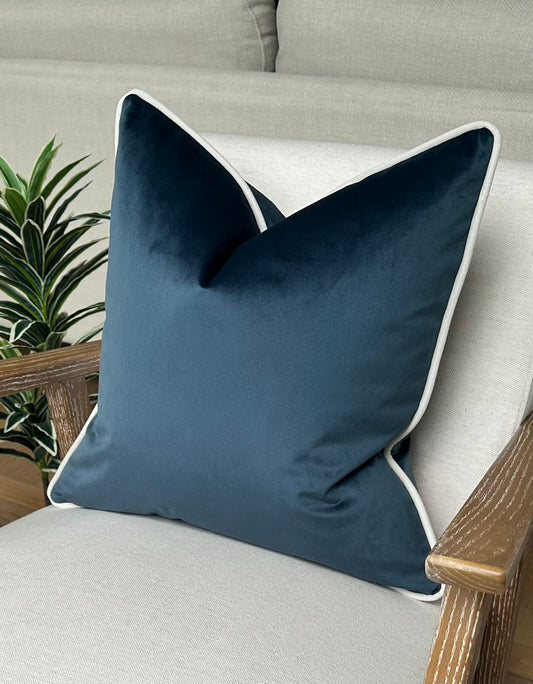 Petrol blue velvet cushion with white piping. 