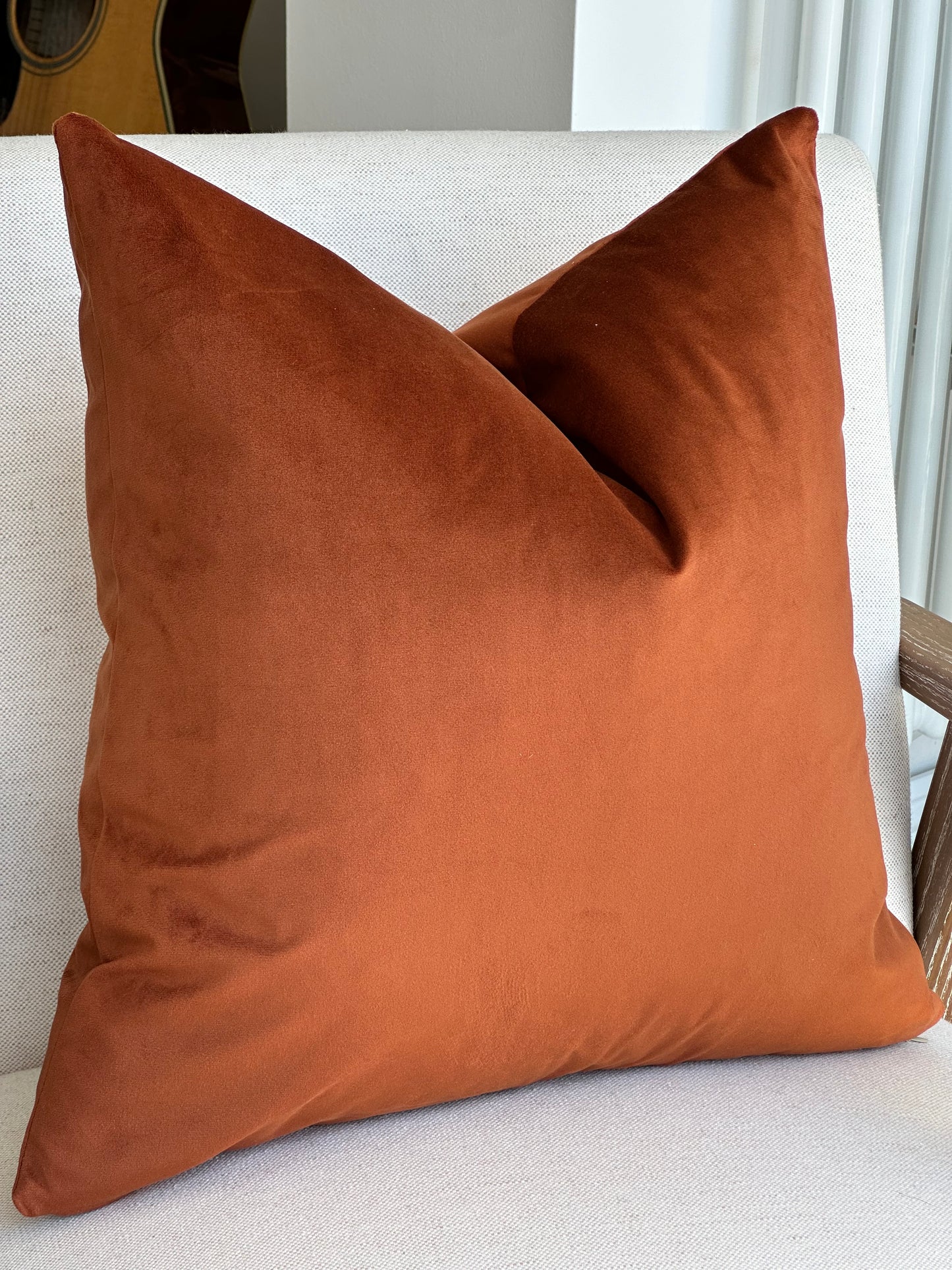 Close-up of a plush burnt orange velvet cushion cover showing its rich, soft texture and deep warm colour.