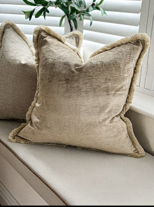 Champagne-beige velvet cushion with matching fringe styled on a neutral window seat.