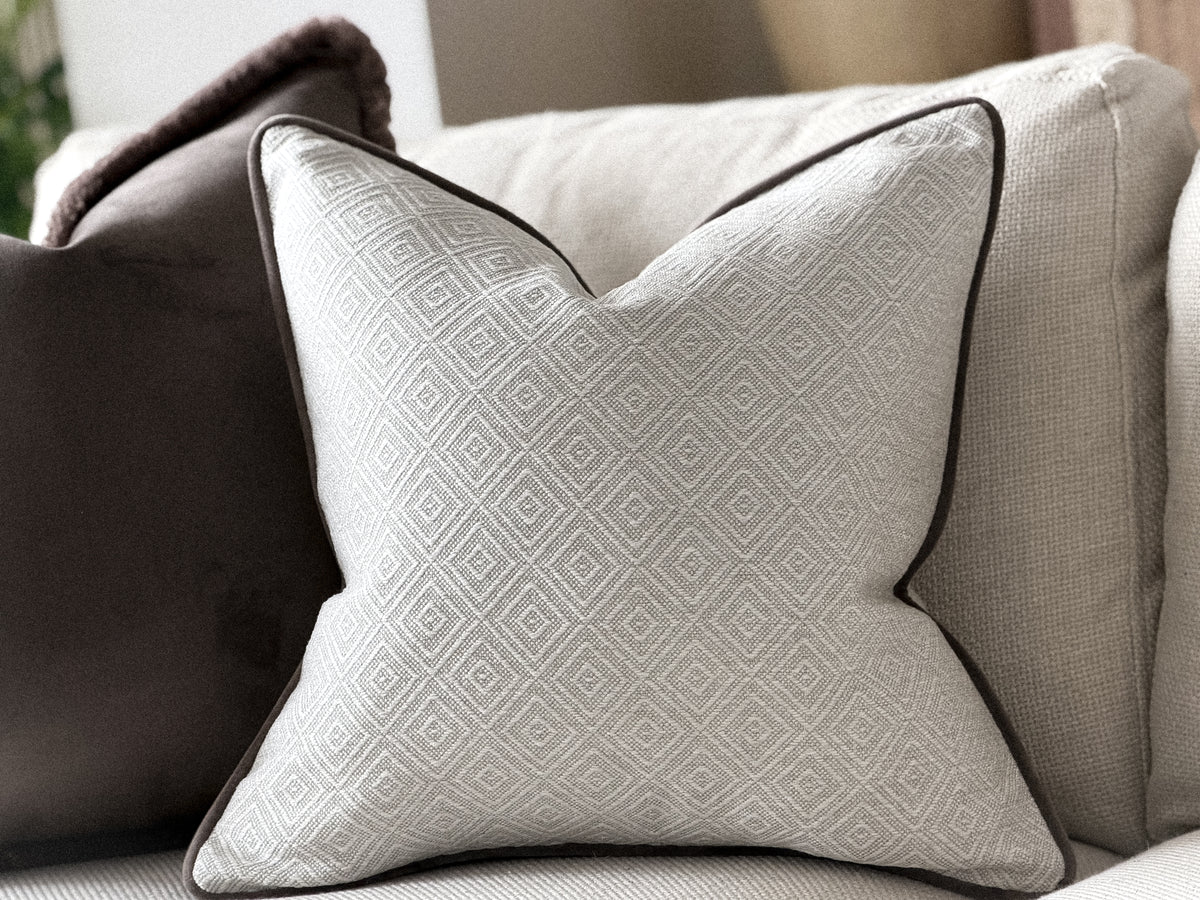 a luxury white decorative pillow with a geometric pattern, placed on a couch.