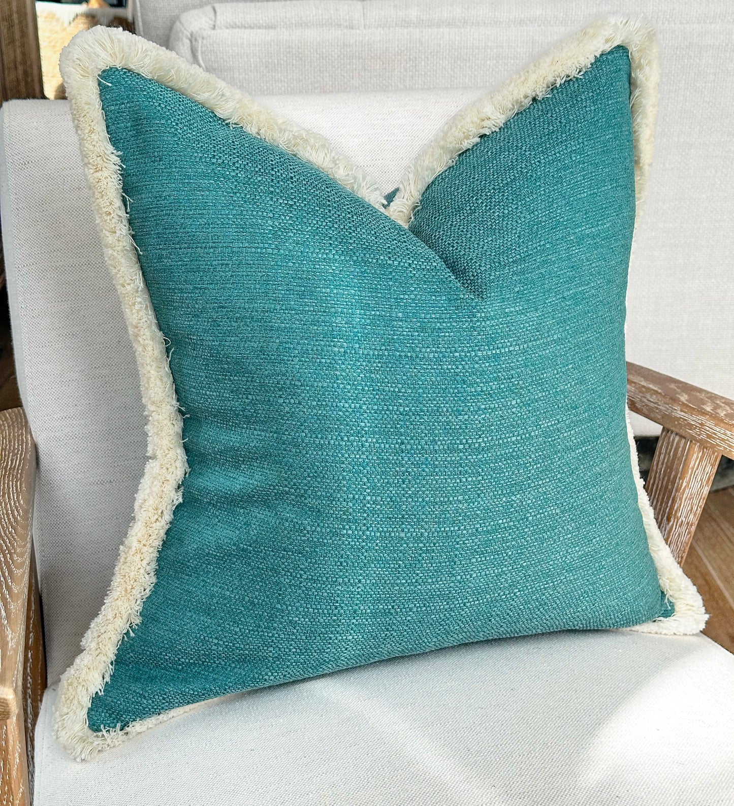 Turquoise blue textured fringed cushion.