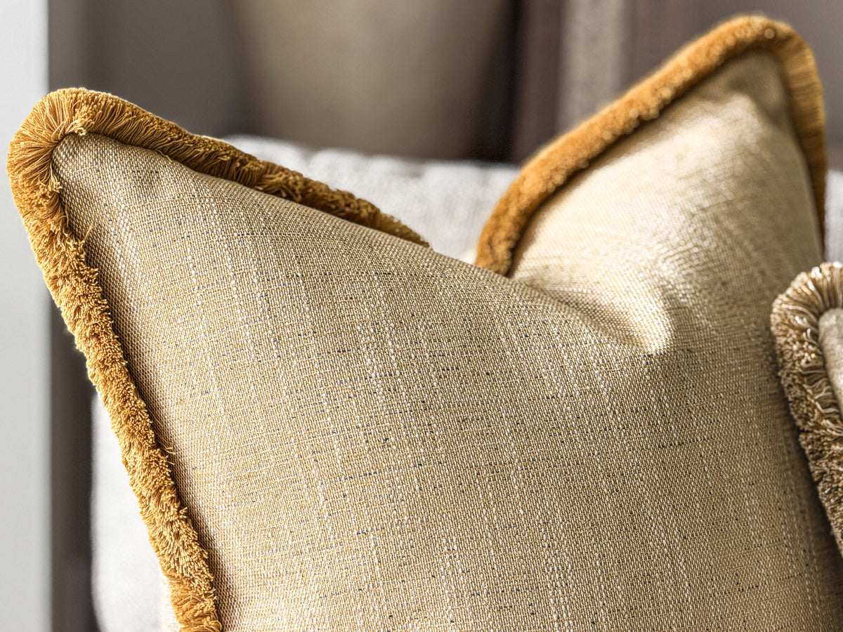 Close-up of a textured yellow throw pillow with a contrasting mustard-gold fringed edge