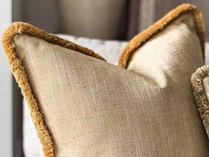 Close-up of a textured yellow throw pillow with a contrasting mustard-gold fringed edge