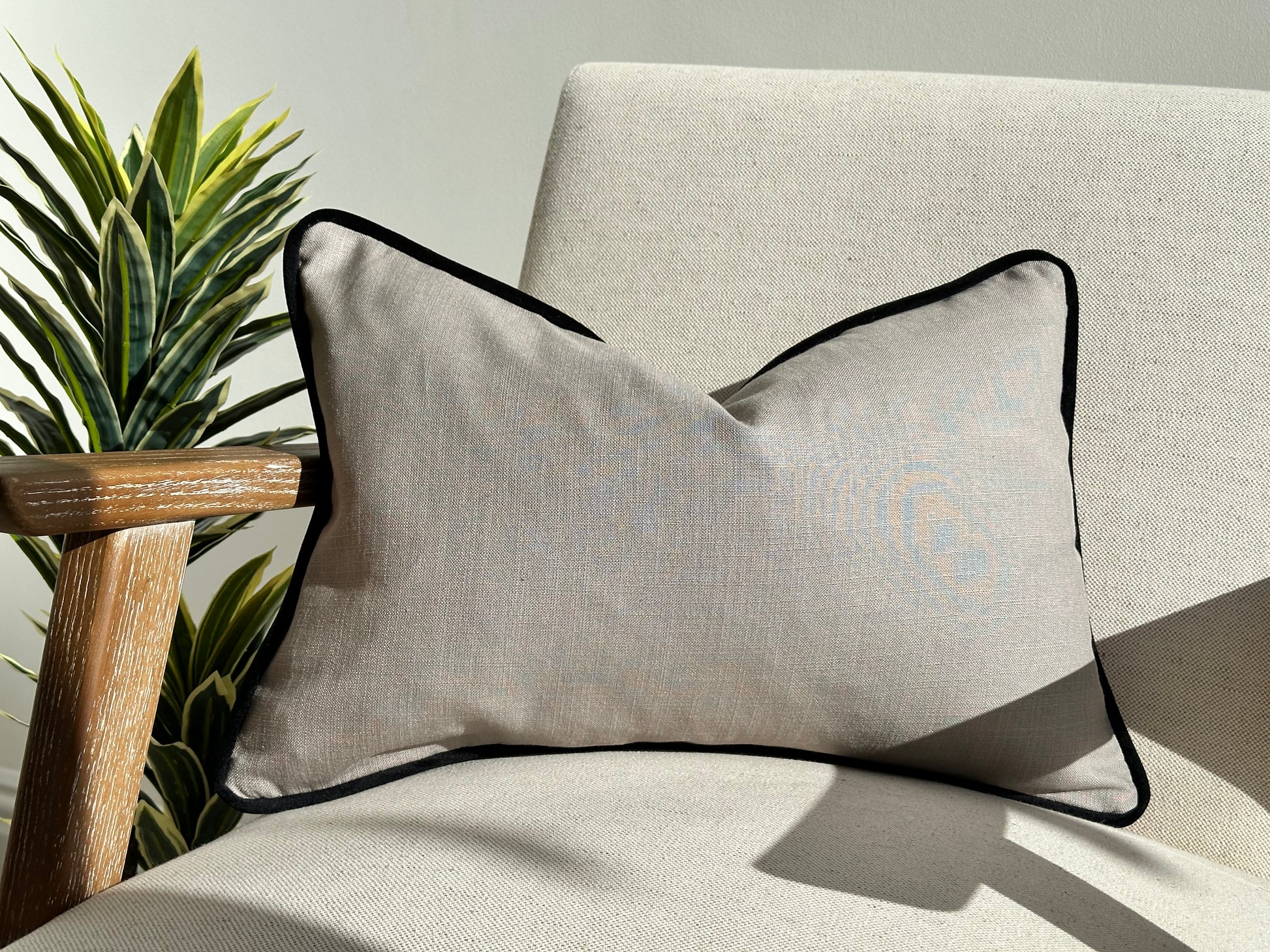 Grey linen cushion with black piping trim.