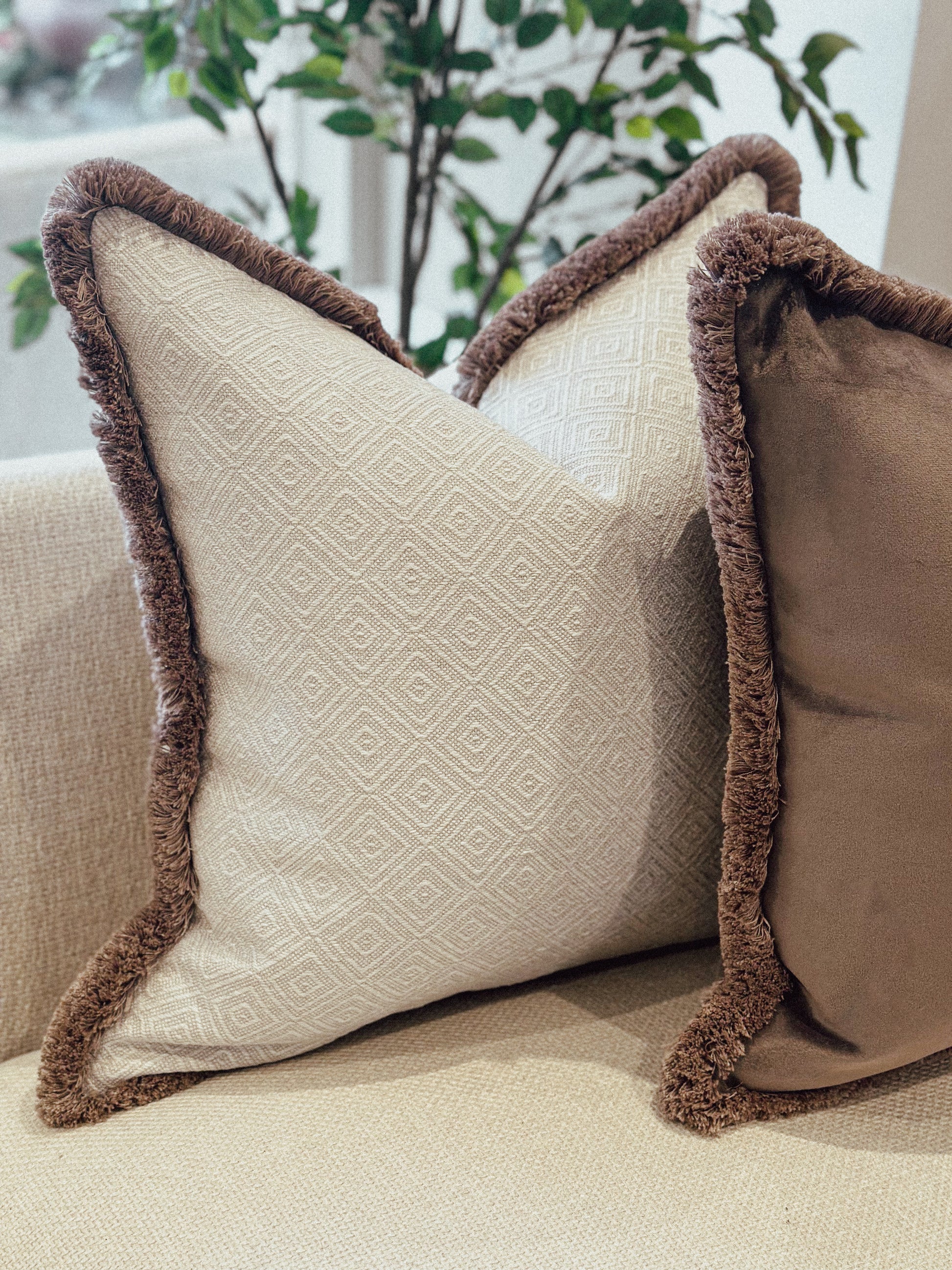 Luxury Natural geometric decorative cushion with brown trim on a beige couch.