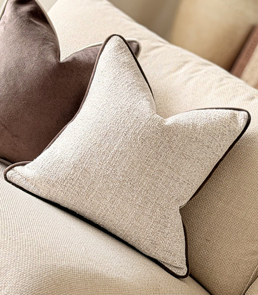 Ivory textured weave fabric cushion with brown piping.