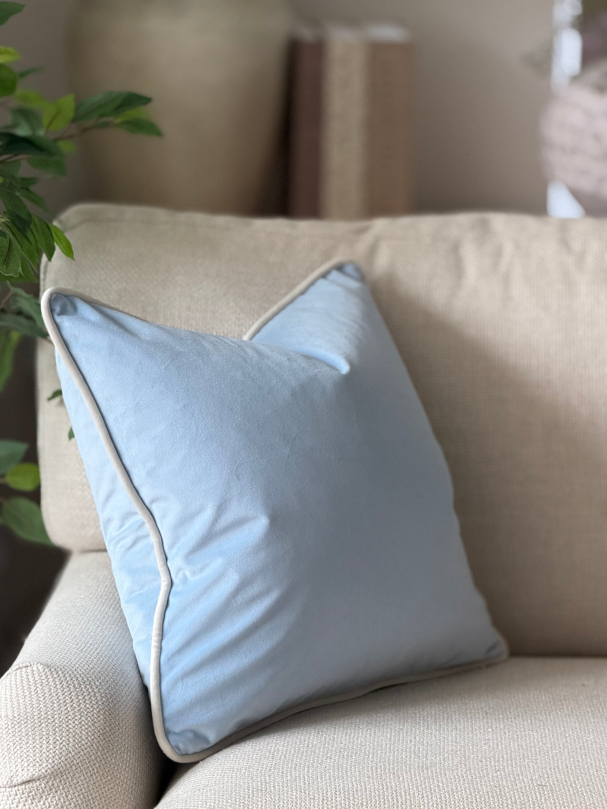 A light blue square throw pillow with a ivory white trim.