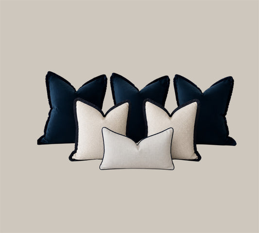 Luxury bed cushion set in dark navy and neutral tones. 