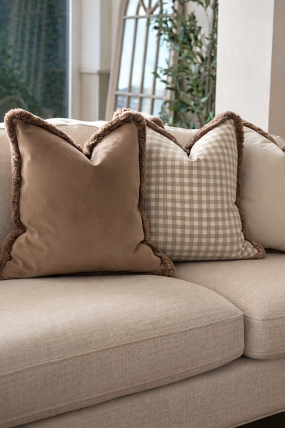Neutral taupe check cushion with plush fringed trim — perfect for modern organic living spaces.