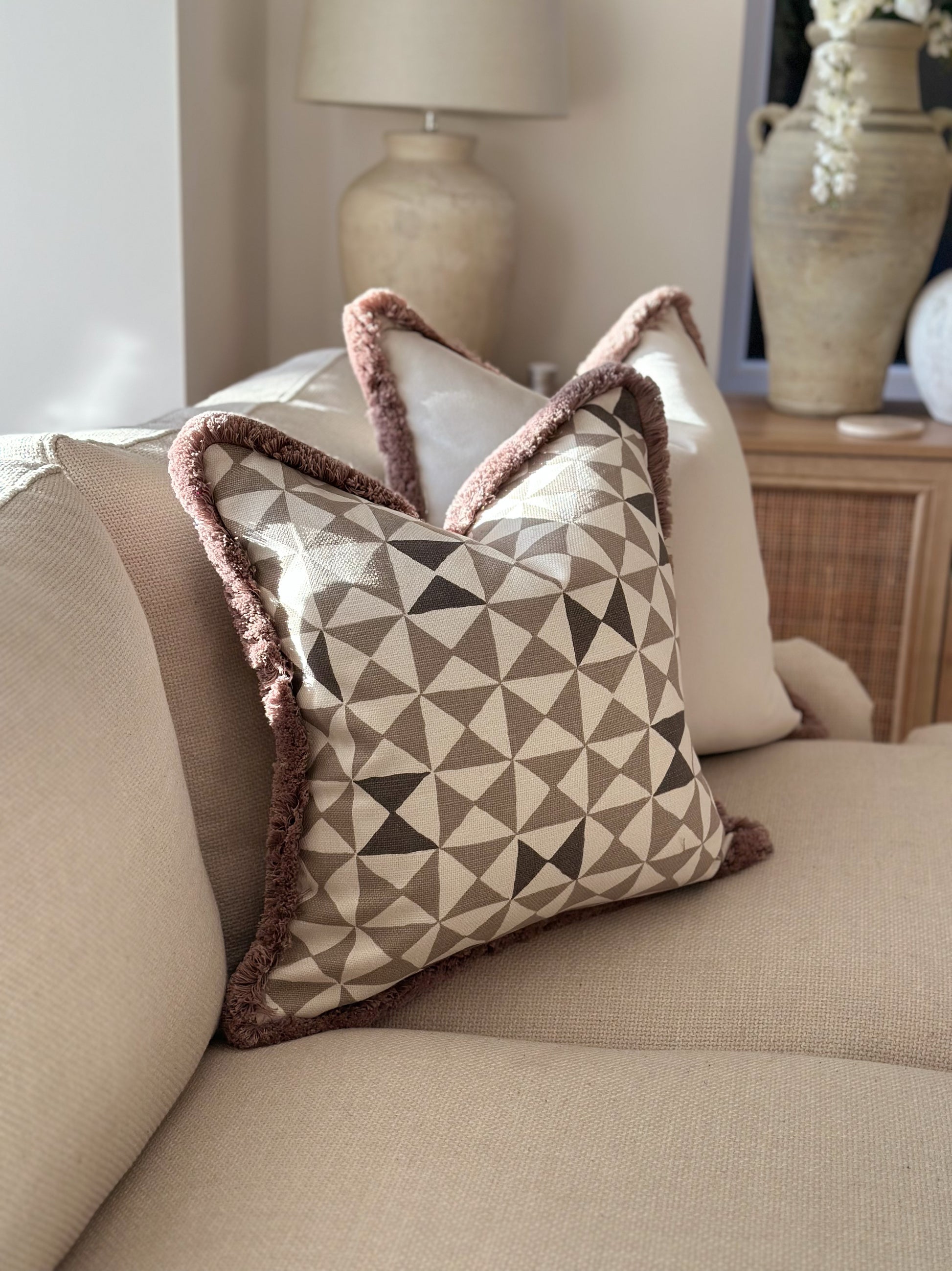 Neutral taupe geometric cushion with plush trim — perfect for modern organic living spaces.